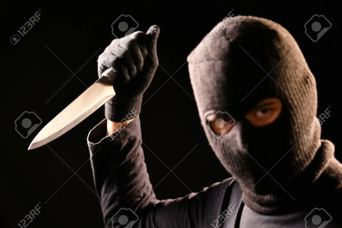 100145367-the-robber-hold-the-knife-in-hand-on-black-background.png